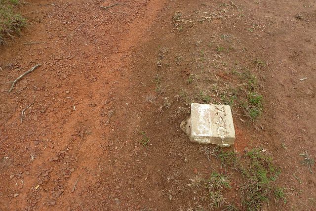 247-Phonsavan-041.jpg - Witte stenen langs de weg geven aan dat hier geen explosieven meer in de grond liggen. Tussen deze wegmarkeringen is het dus veilig lopen.