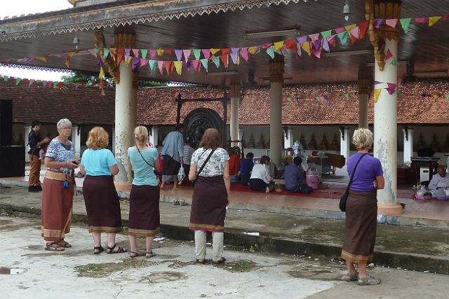 399-savannakhet-011.jpg - Vrouwen mogen de stoepa niet binnen zonder een traditionele Laotiaanse sarong. Dus draperen we ons maar met zo’n stuk stof.