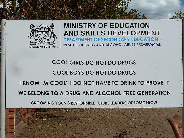 587-okavangodelta-169.jpg - Het is vakantie. De kinderen zijn niet op school, maar het preventiebord tegen alcohol en drugs staat er wel.
